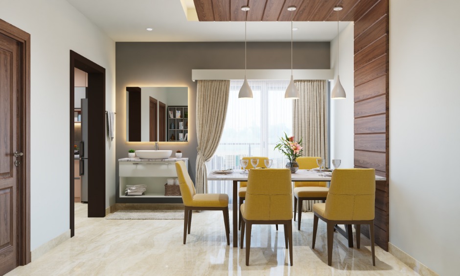1bhk small dining area with a marble top dining table and four yellow chairs make up a cosy corner