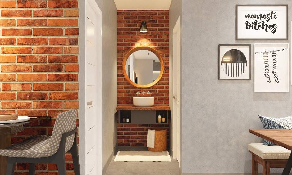 A small vanity unit in a 1bhk design with a floating shelf, a round mirror and a sink fit in the compact space