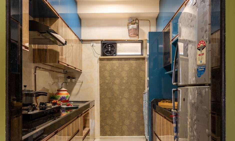 Completed parallel kitchen project in Kandivali West with wooden laminate base and blue wall cabinets.