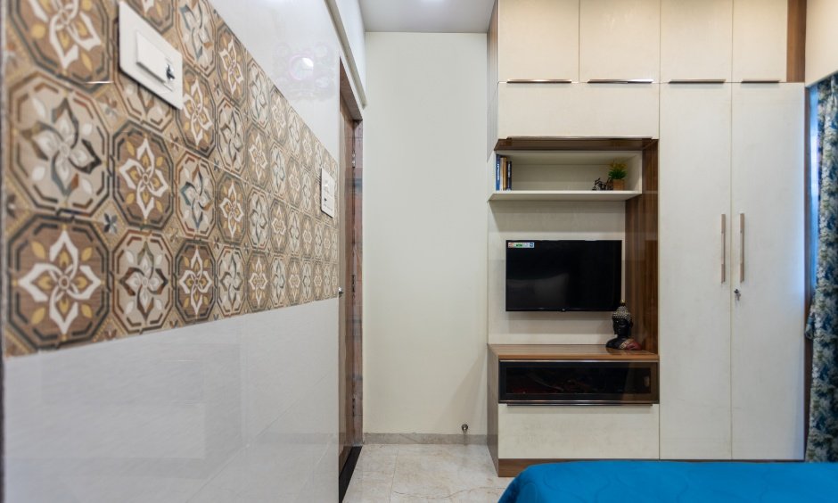 A wardrobe in guest bedroom has a design that includes a TV unit in Ulwe, Navi Mumbai